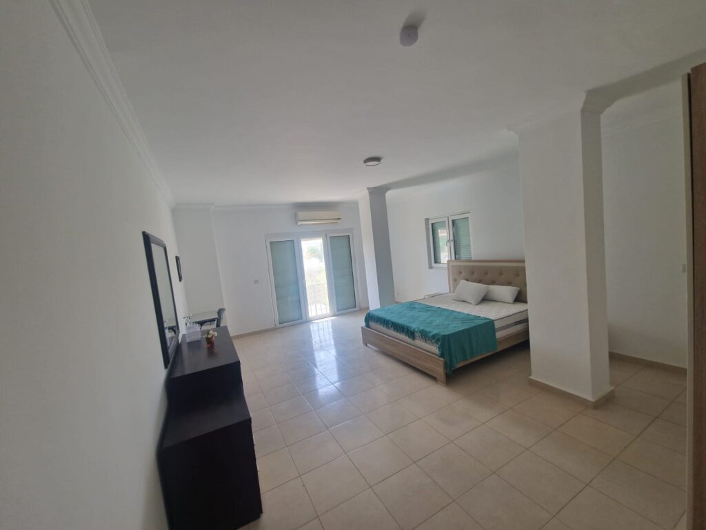 Geräumiges, helles Schlafzimmer mit Doppelbett und Balkon.